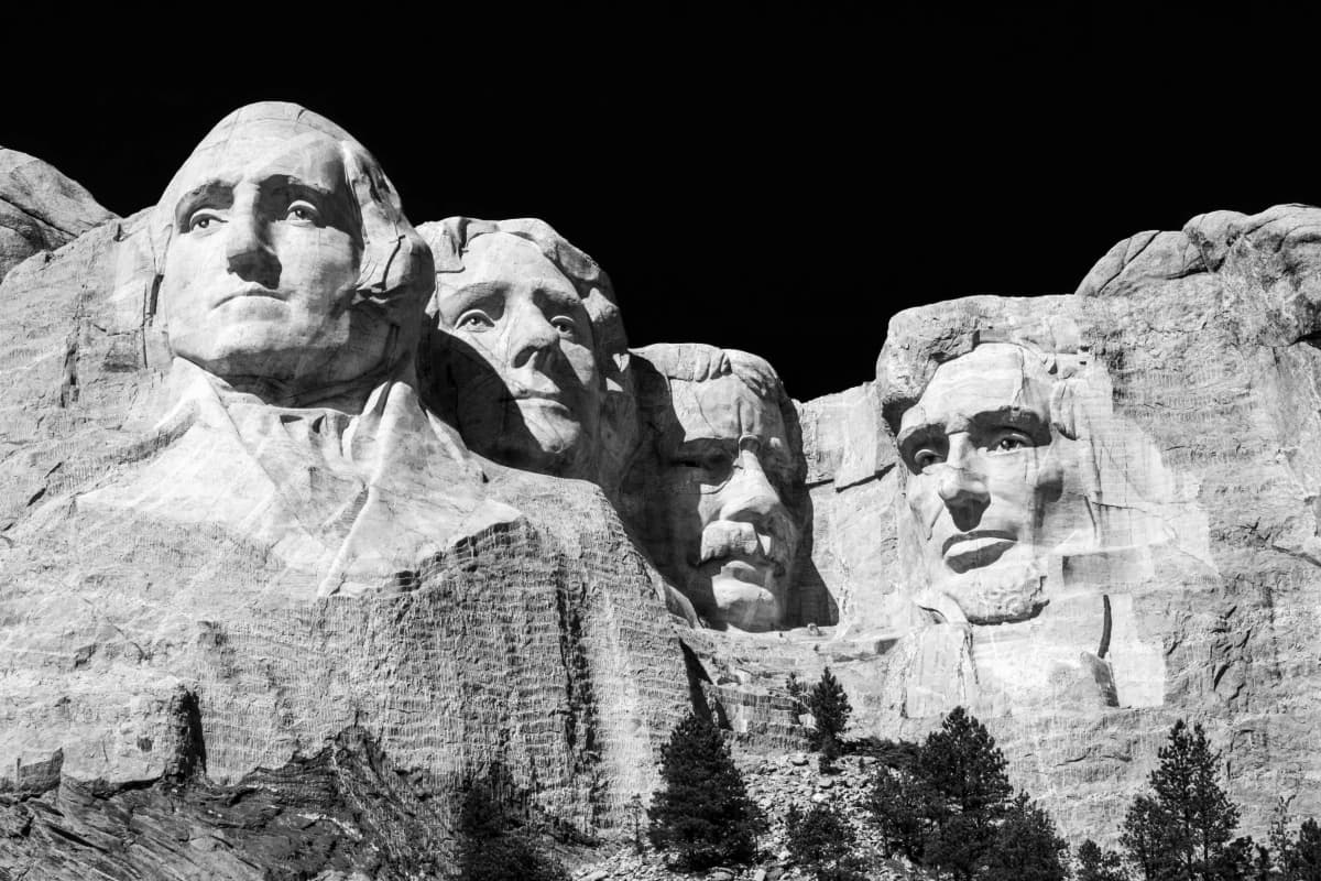 The granite faces of Mount Rushmore carved into the Black Hills under a blue sky