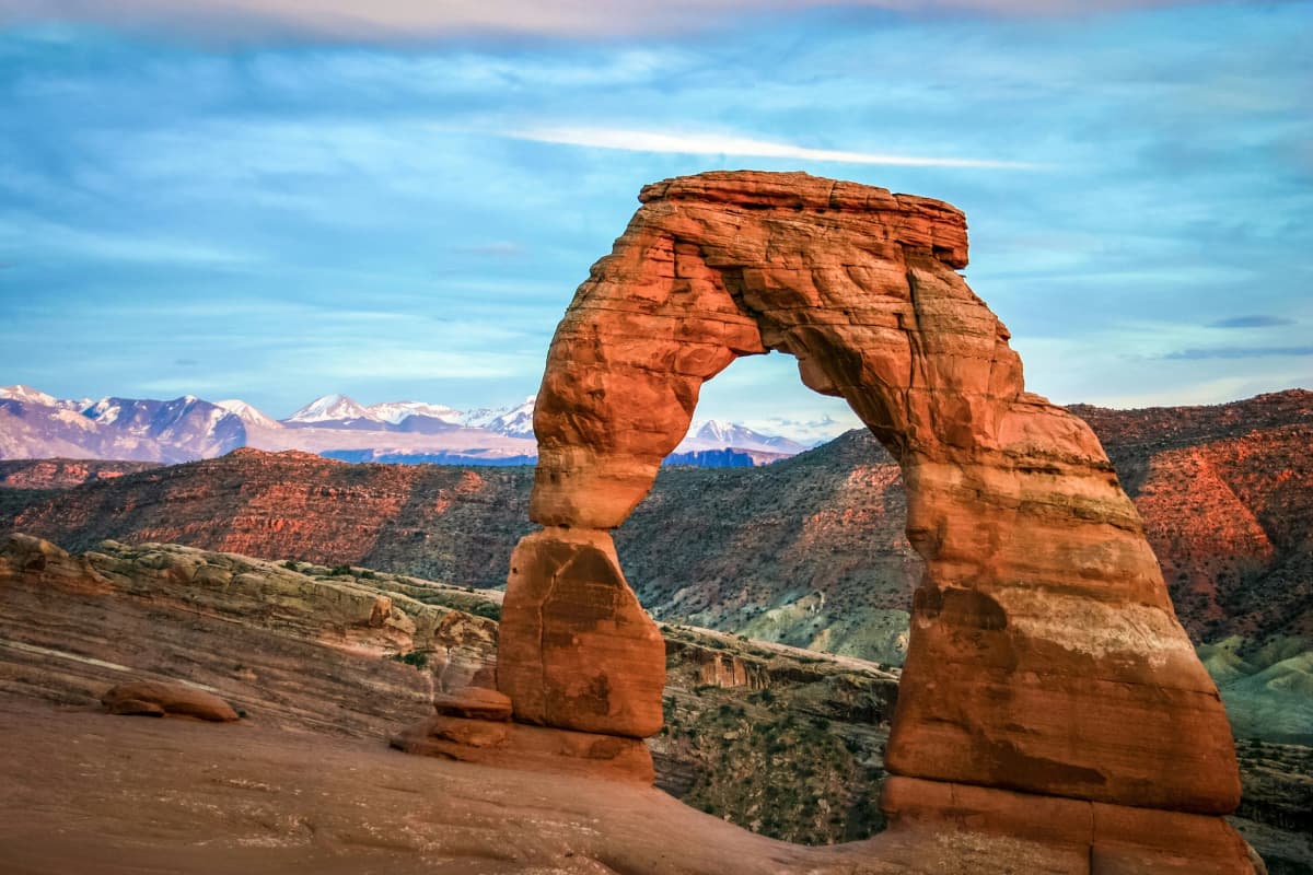 Delicate Arch standing over red sandstone in Arches National Park, Utah, at sunset