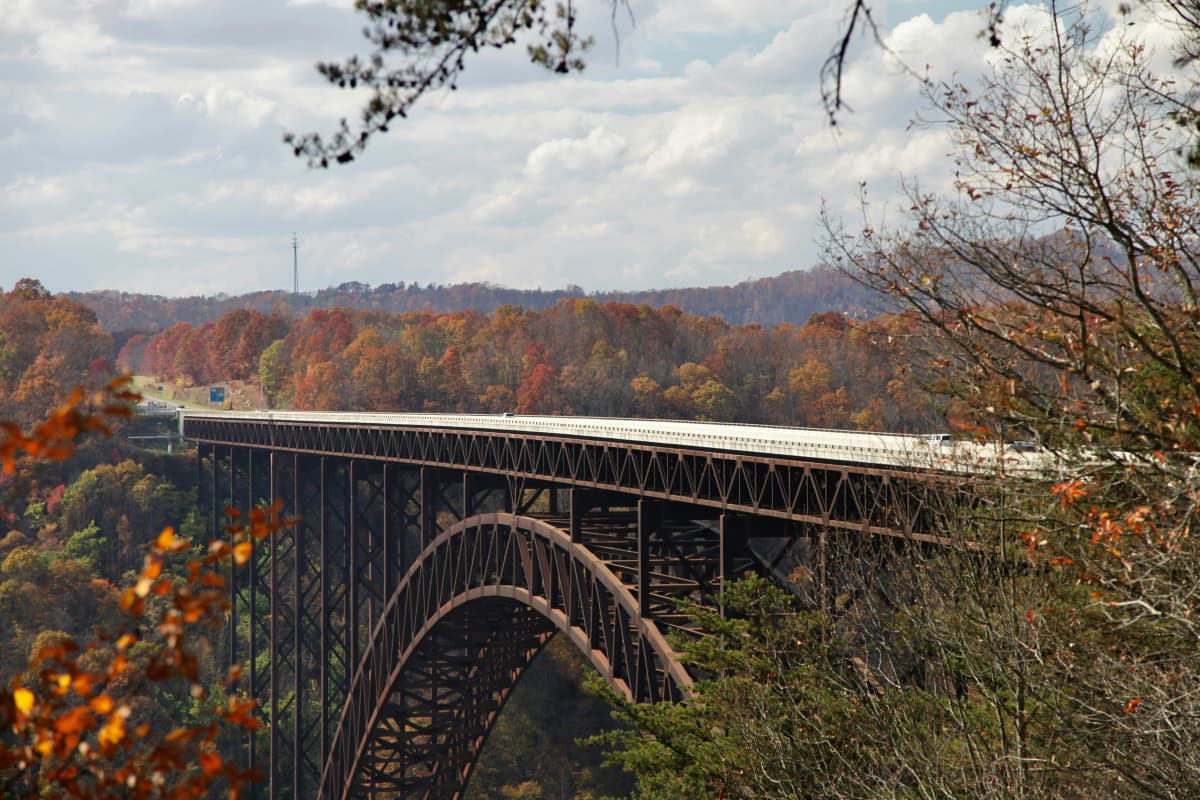 The steel arch of the New River Gorge Bridge spanning a forested gorge in fall color, West Virginia