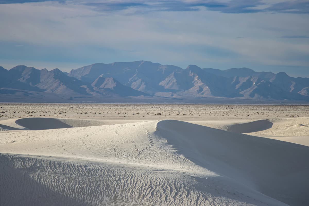 Rippled white gypsum dunes stretching toward the mountains at White Sands National Park, New Mexico