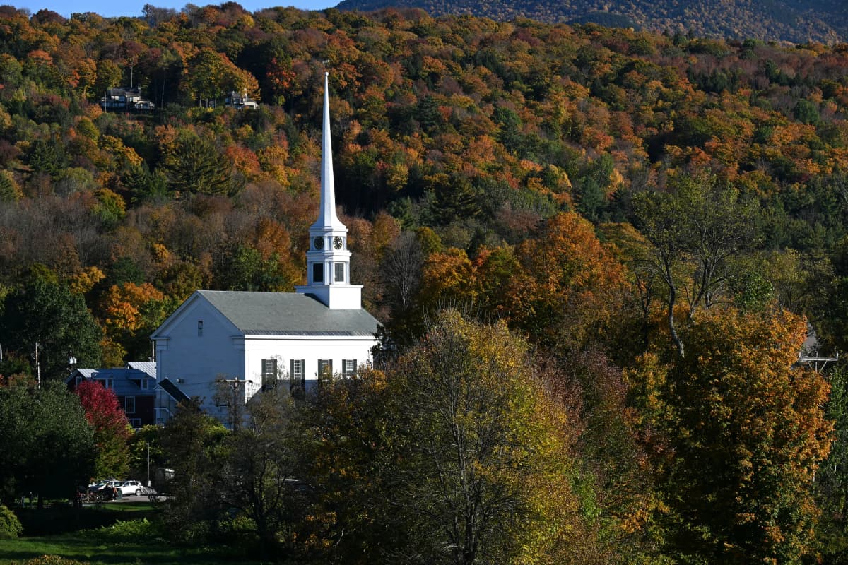 White steeple of Stowe Community Church against fall foliage and Mount Mansfield in Stowe, Vermont